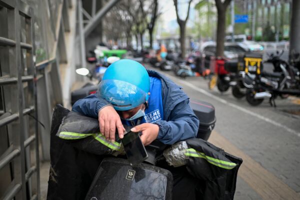 示意图。图为2023年4月1日,北京一位外卖员在电动车上休息。(WANG ZHAO/AFP via Getty Images)