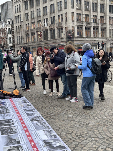 广场上的游人,观看并拍摄地上的海报。(活动义工江培坤提供)