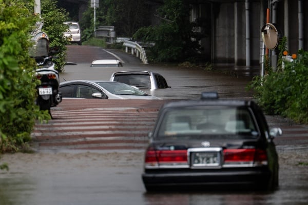 2026年8月14日,日本千叶县佐仓市,一条被洪水淹没的道路上,多辆被遗弃的汽车部分浸在水中。